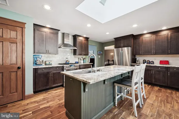 a kitchen with stainless steel appliances kitchen island granite countertop a stove a sink and a refrigerator