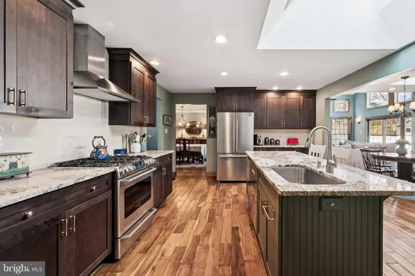 a kitchen with kitchen island granite countertop a sink a counter top space stainless steel appliances and cabinets