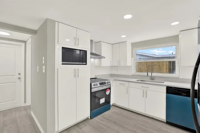 a kitchen with stainless steel appliances granite countertop a stove top oven a sink and dishwasher with wooden floor