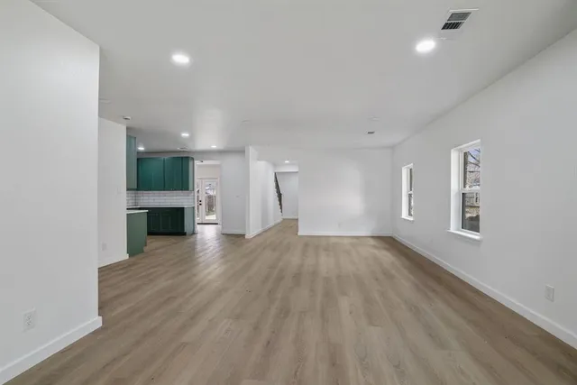a view of empty room with wooden floor and windows