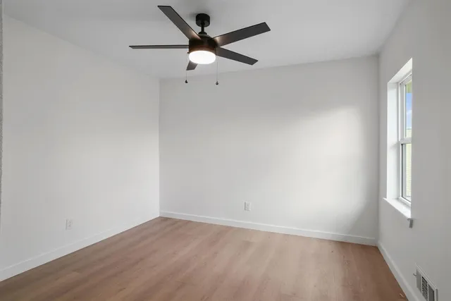 an empty room with a window and a fan