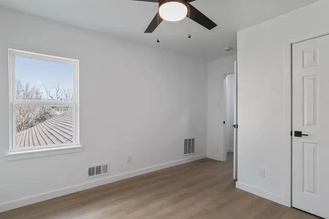 a view of an empty room with window and wooden floor