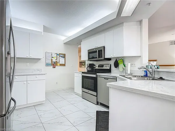 a kitchen with granite countertop white cabinets stainless steel appliances and a window