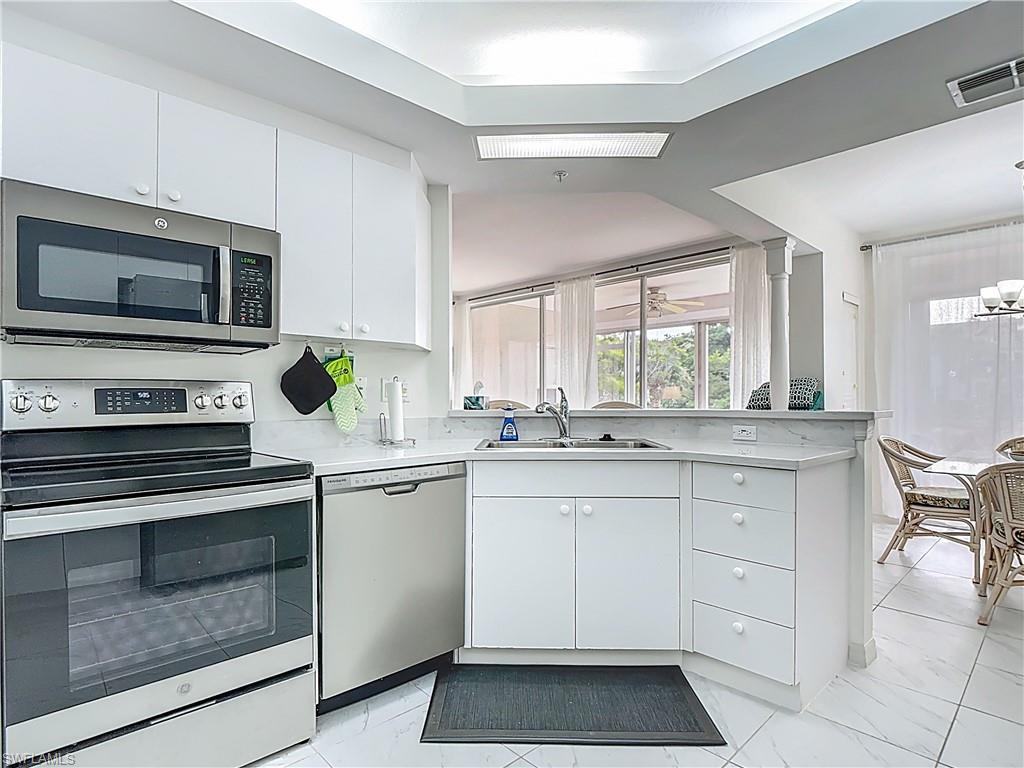 6834 Lantana Bridge Road, Unit 102 Naples, FL 34109 - Photo 19 of 45 a kitchen with granite countertop white cabinets stainless steel appliances and a window