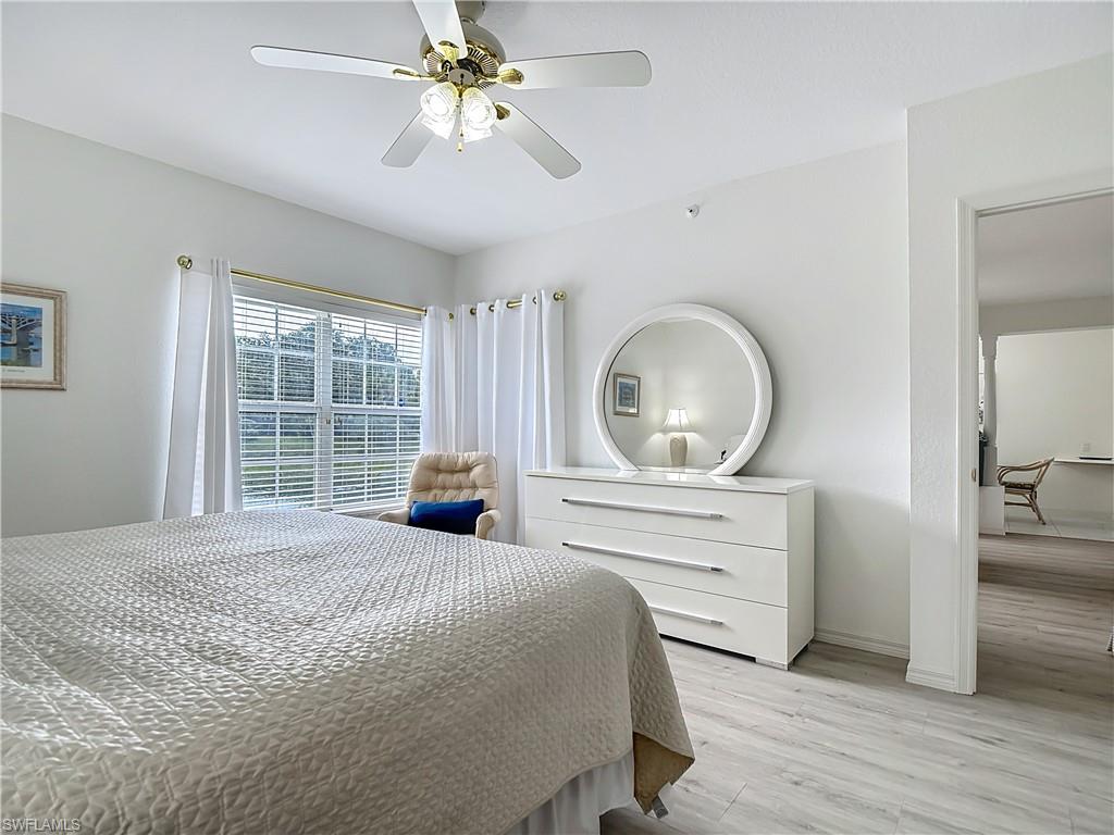 6834 Lantana Bridge Road, Unit 102 Naples, FL 34109 - Photo 26 of 45 a bedroom with a bed a window and a chandelier