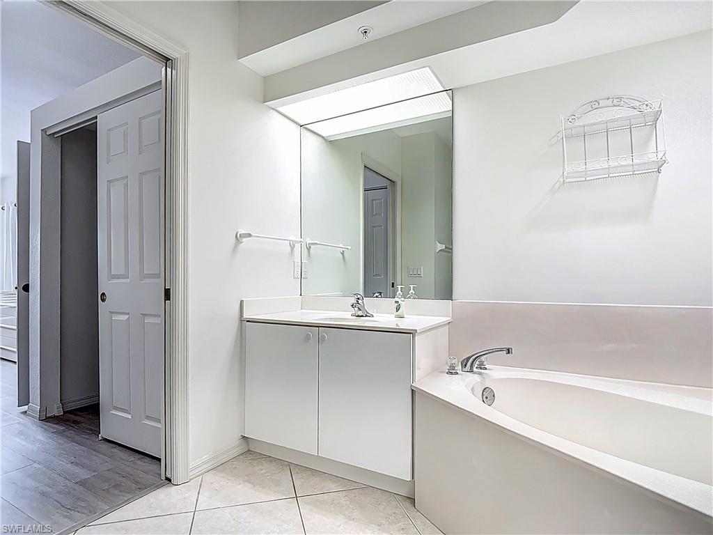 6834 Lantana Bridge Road, Unit 102 Naples, FL 34109 - Photo 32 of 45 a bathroom with a tub sink and mirror
