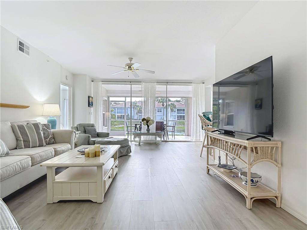 6834 Lantana Bridge Road, Unit 102 Naples, FL 34109 - Photo 8 of 45 a living room with furniture flat screen tv and large window