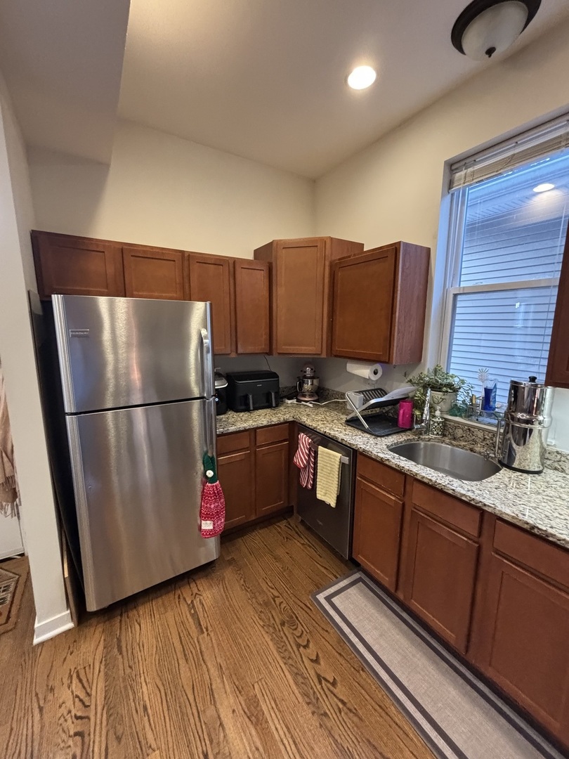 1644 North Hermitage Avenue, Unit 2R Chicago, IL 60622 - Photo 6 of 18 a kitchen with granite countertop a refrigerator stove and wooden cabinets