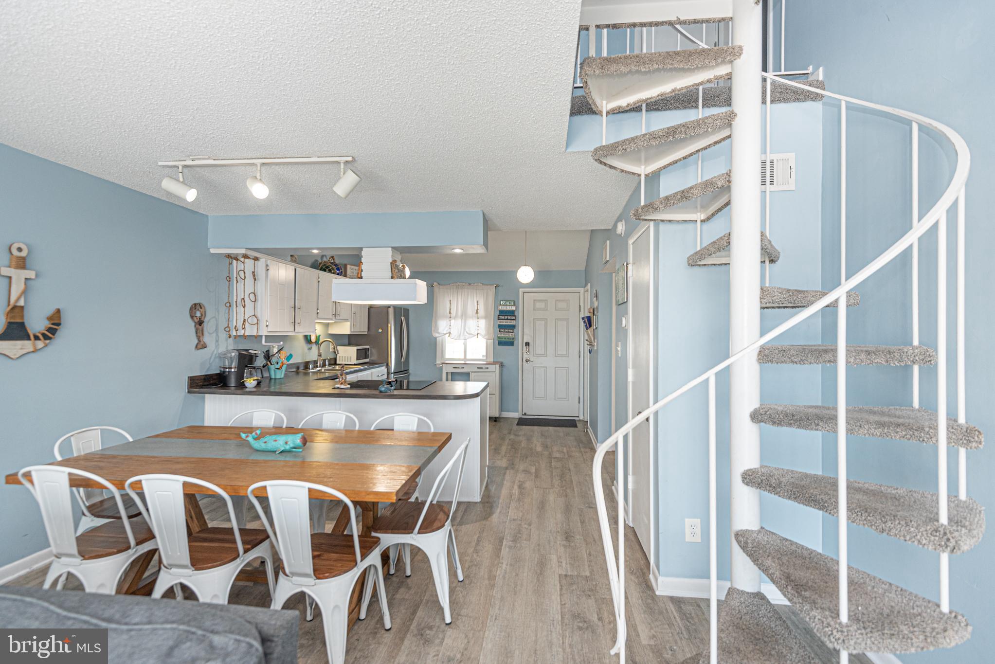 9203 Rusty Anchor Road, Unit A5 Ocean City, MD 21842 - Photo 14 of 60 a kitchen with kitchen island granite countertop wooden floor and a refrigerator