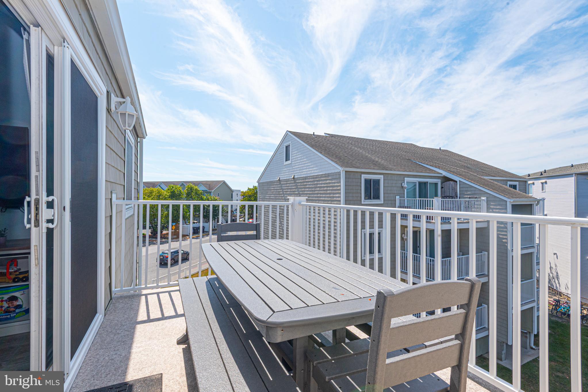 9203 Rusty Anchor Road, Unit A5 Ocean City, MD 21842 - Photo 31 of 60 a balcony of a house with wooden floor outdoor seating and yard in the back