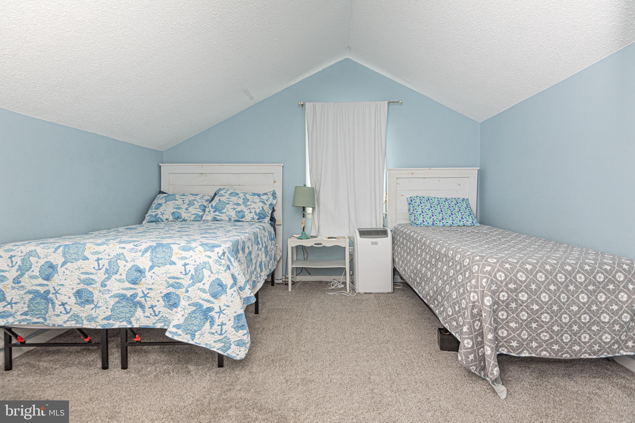 9203 Rusty Anchor Road, Unit A5 Ocean City, MD 21842 - Photo 45 of 60 a bedroom with a bed and a lamp on dresser