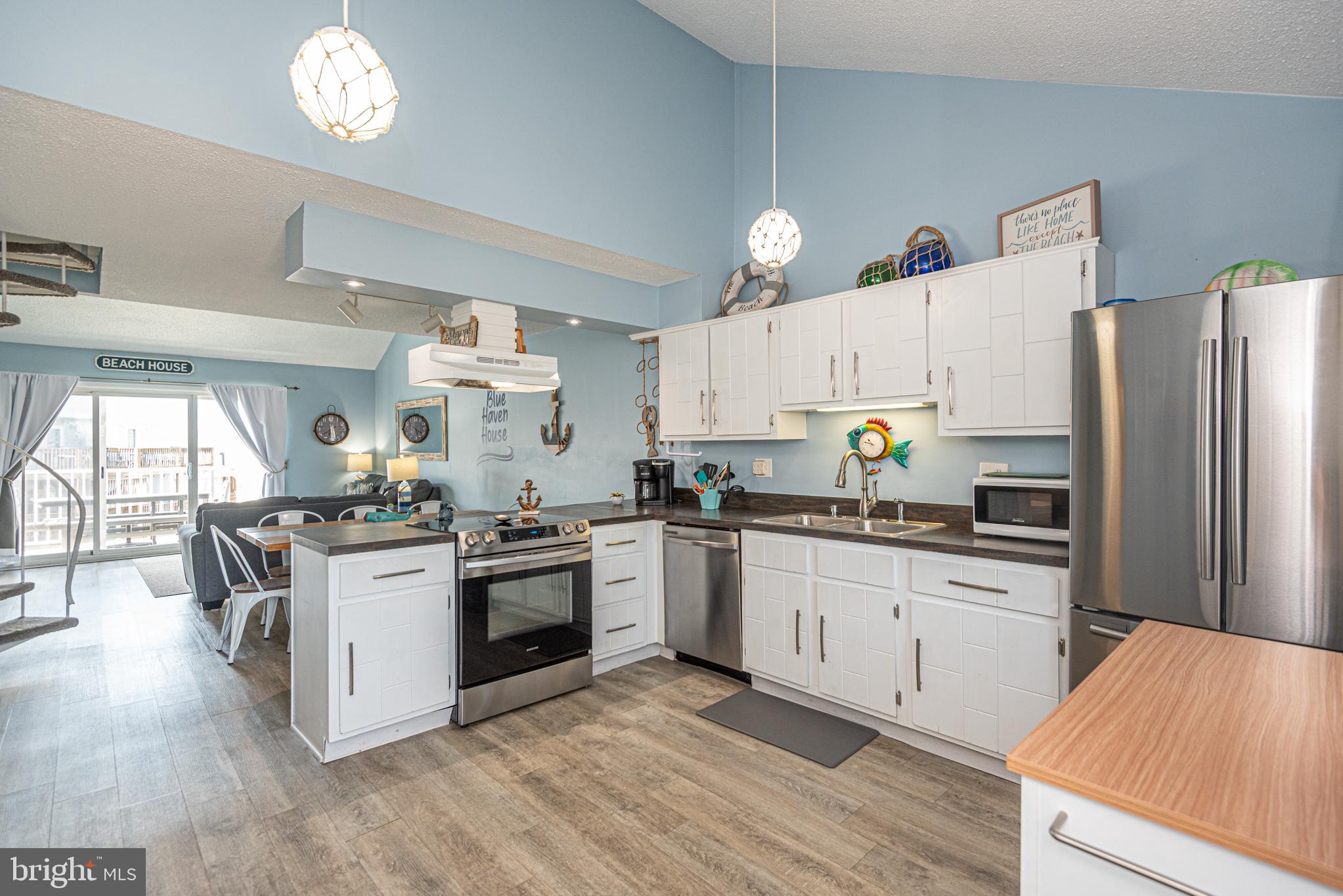 9203 Rusty Anchor Road, Unit A5 Ocean City, MD 21842 - Photo 5 of 60 a kitchen with stainless steel appliances granite countertop a stove top oven a refrigerator a sink and dishwasher with wooden floor