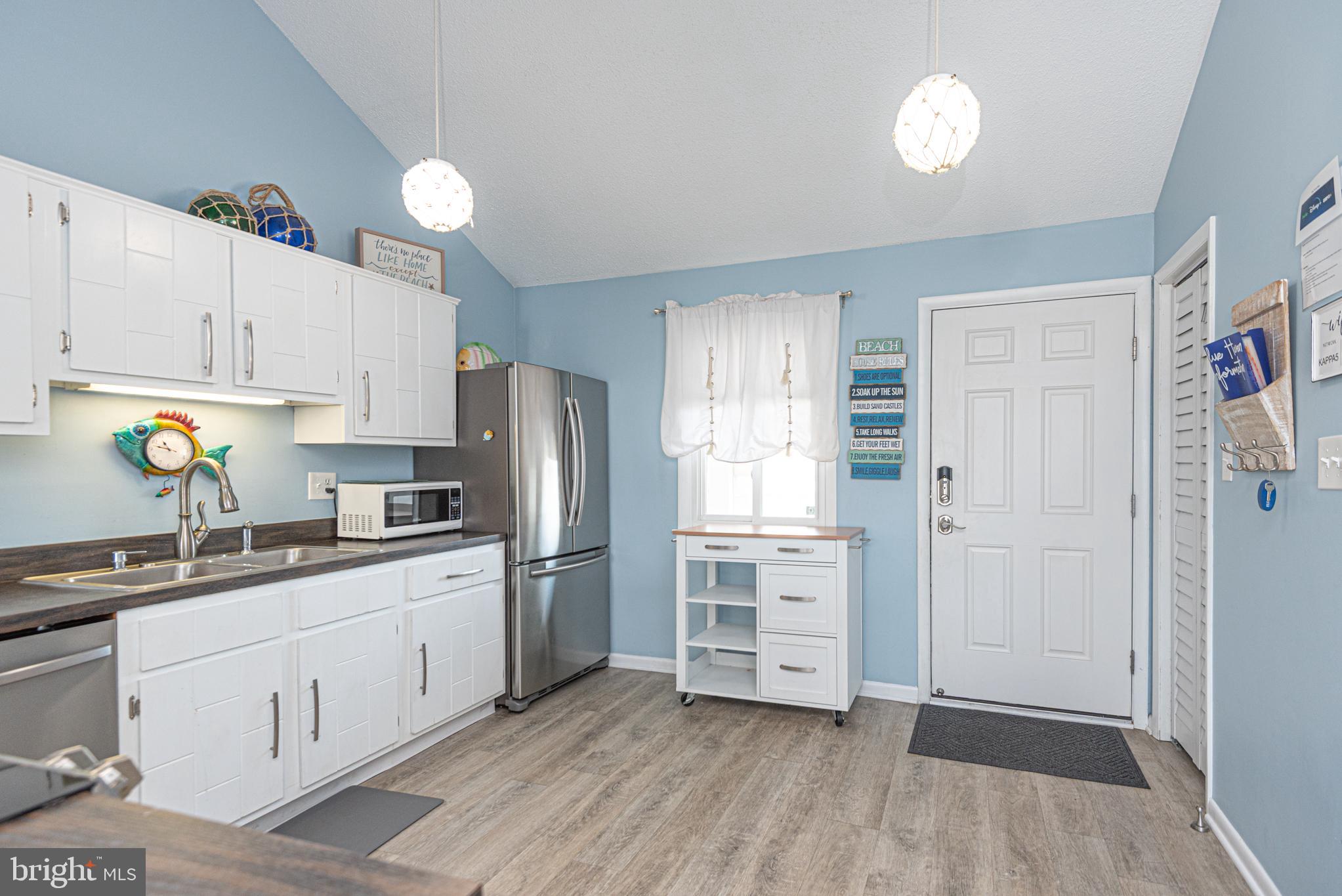 9203 Rusty Anchor Road, Unit A5 Ocean City, MD 21842 - Photo 10 of 60 a kitchen with white cabinets and stainless steel appliances