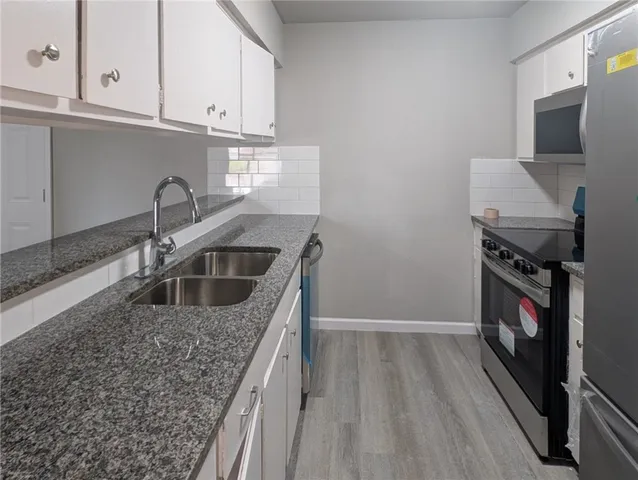 a kitchen with stainless steel appliances granite countertop a sink stove and cabinets