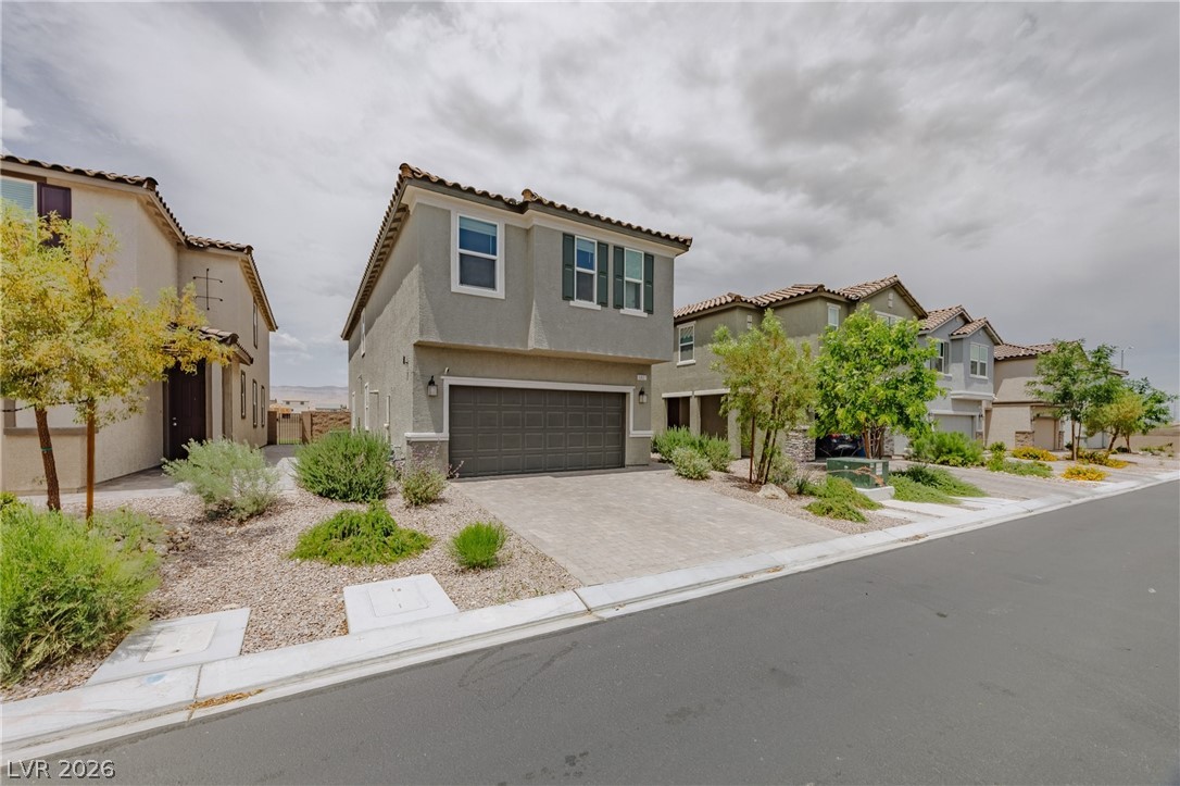 5927 Coja Street Las Vegas, NV 89113 - Photo 2 of 32 View of front of home with stucco siding, a garage, decorative driveway, a tiled roof, and a residential view