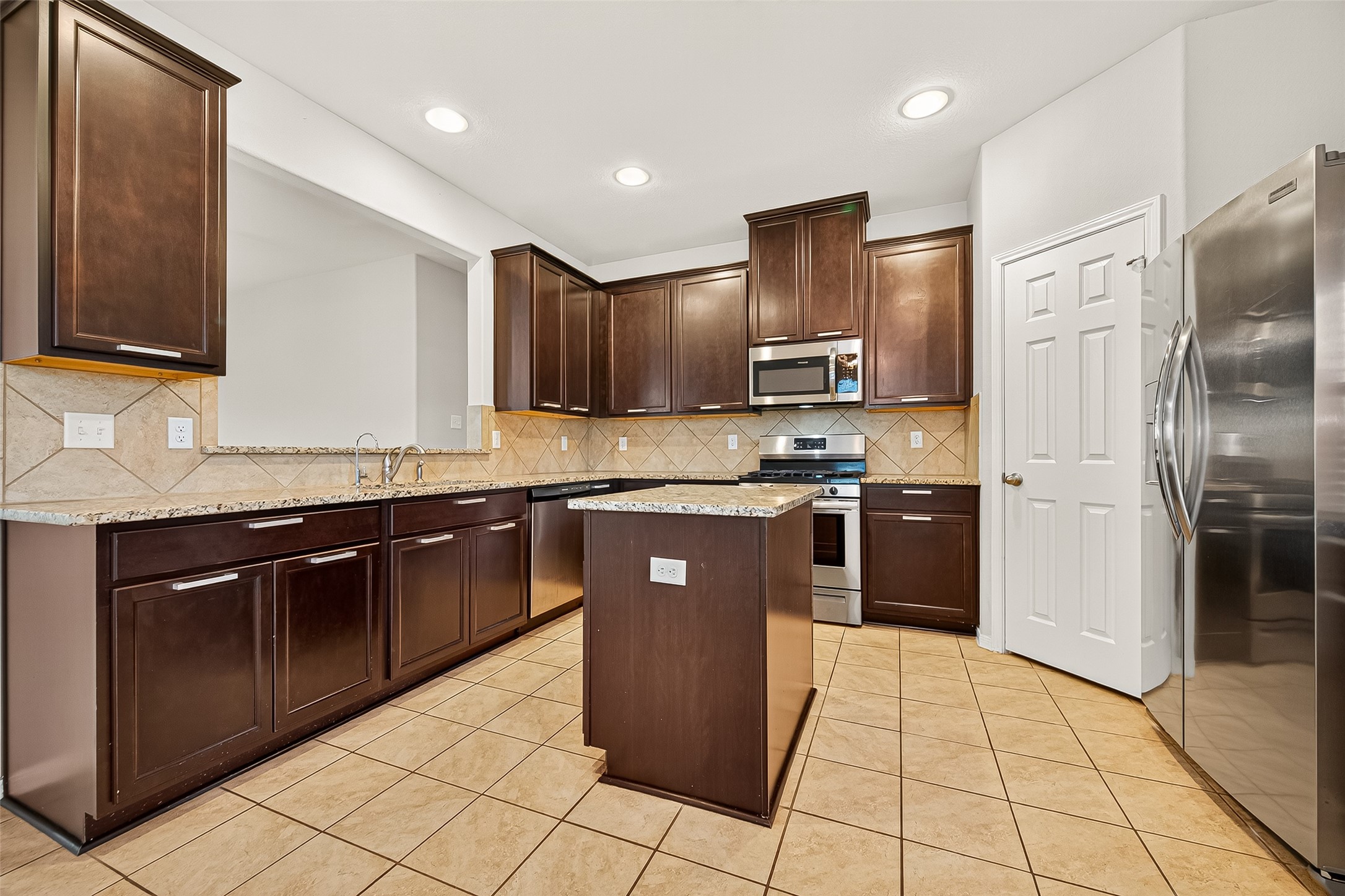 7219 Victorville Drive Rosharon, TX 77583 - Photo 11 of 34 a kitchen with stainless steel appliances granite countertop wooden cabinets a refrigerator and a sink