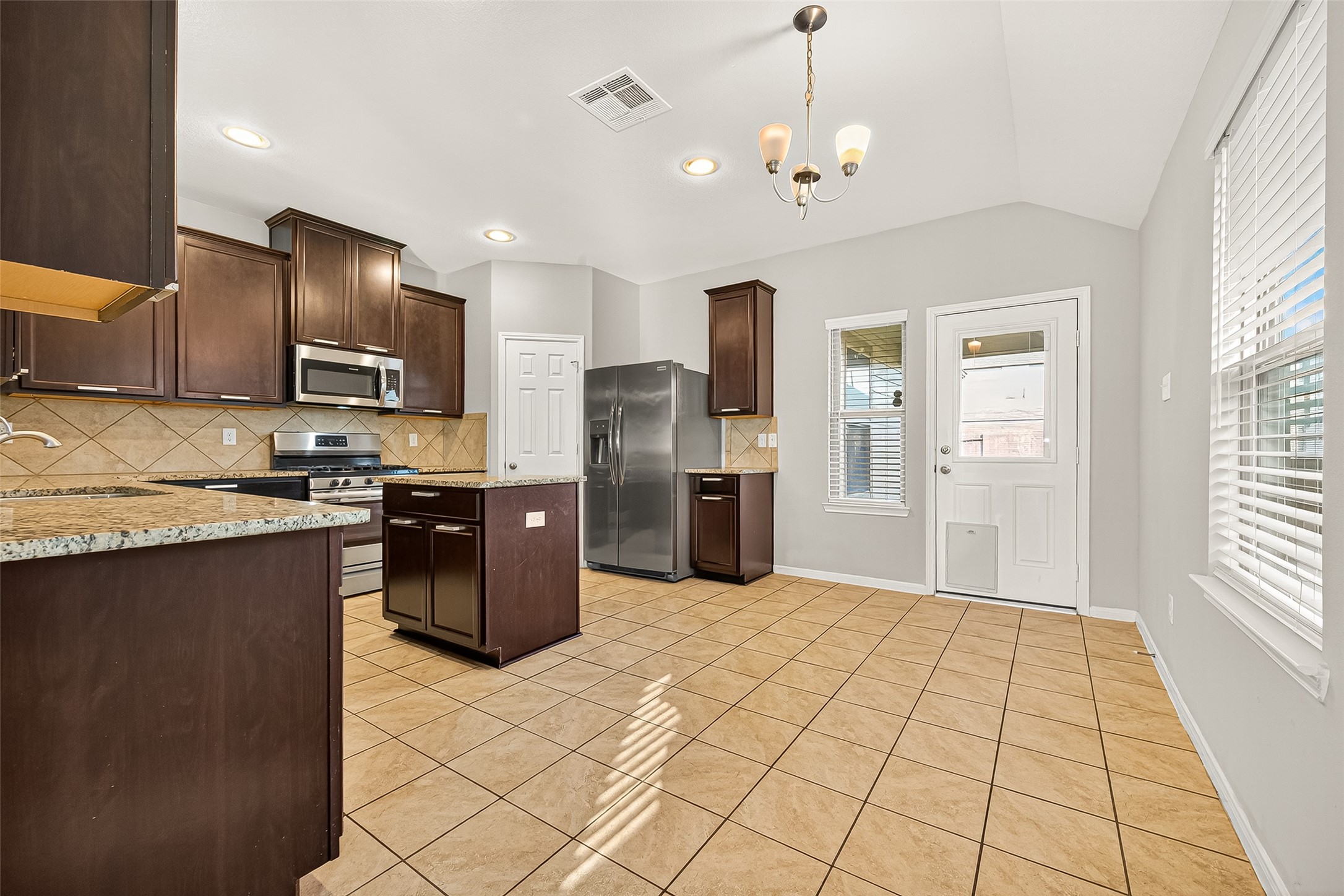 7219 Victorville Drive Rosharon, TX 77583 - Photo 8 of 34 a kitchen with granite countertop a refrigerator and a stove top oven