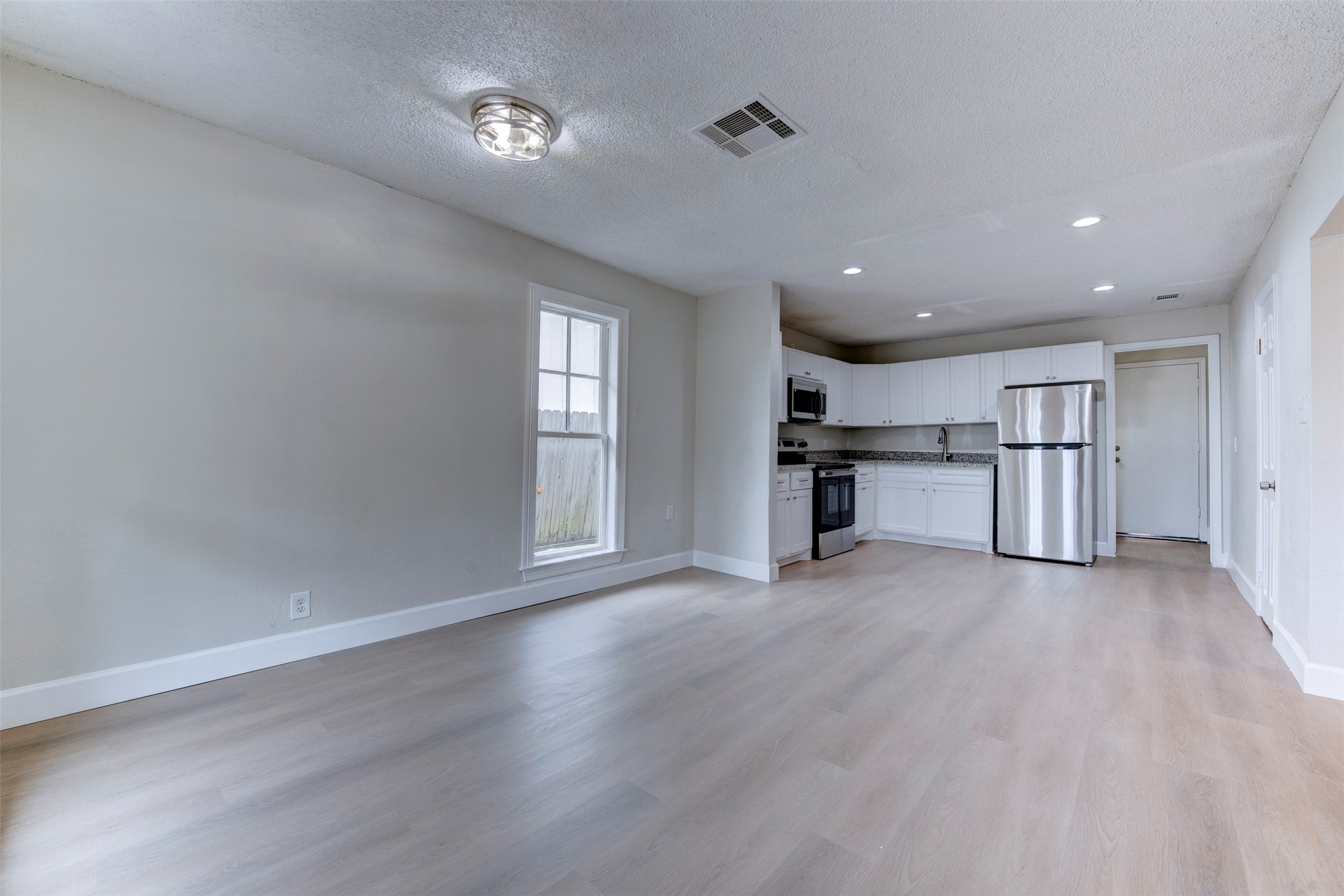 2127 Maximilian Street, Unit 10 Houston, TX 77039 - Photo 5 of 11 a view of empty room with wooden floor and kitchen