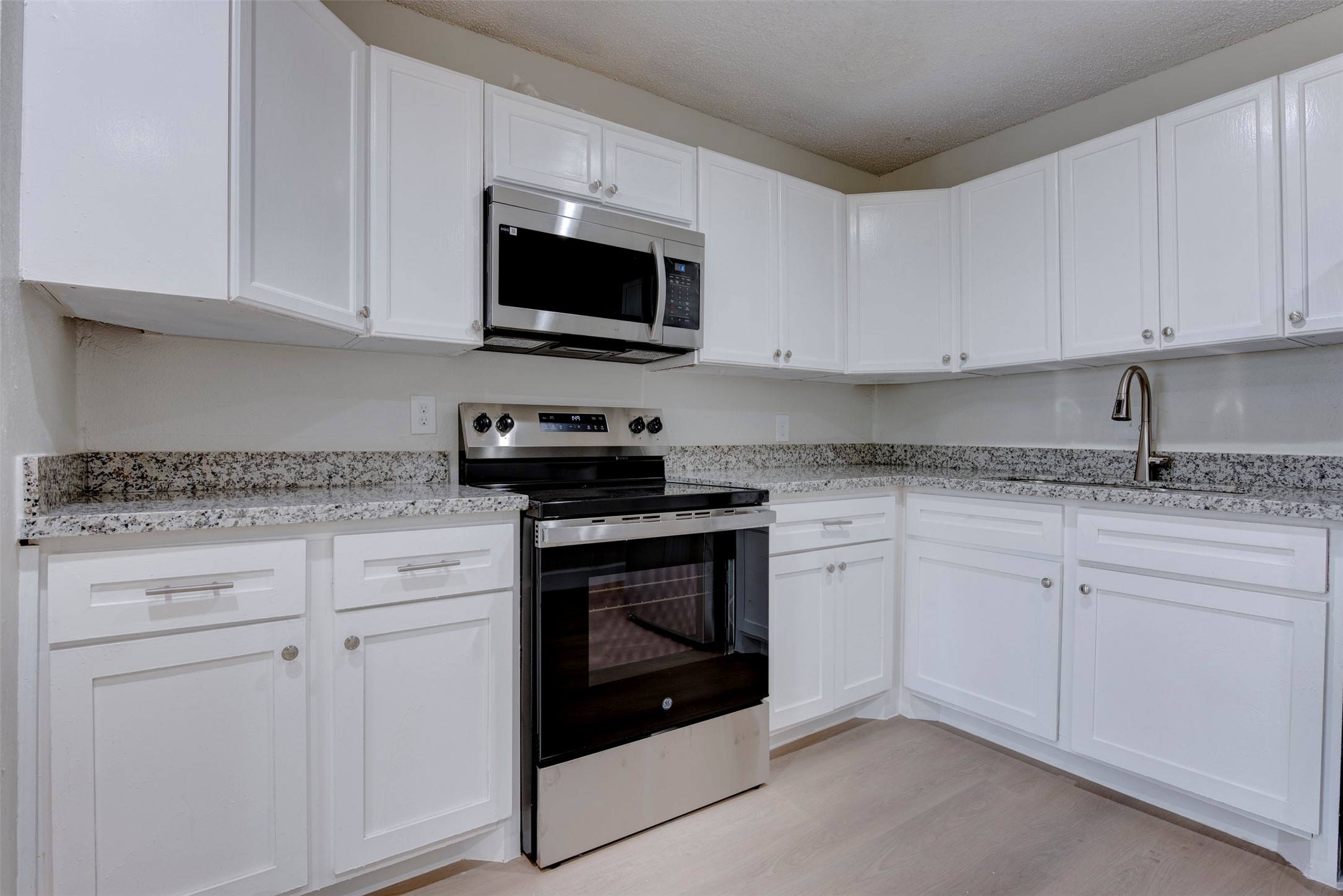 2127 Maximilian Street, Unit 10 Houston, TX 77039 - Photo 7 of 11 a kitchen with white cabinets granite counter tops and a stove