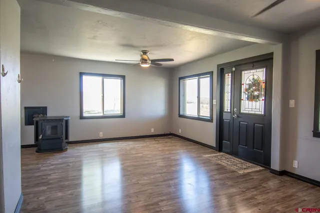 a view of an empty room with a window and wooden floor