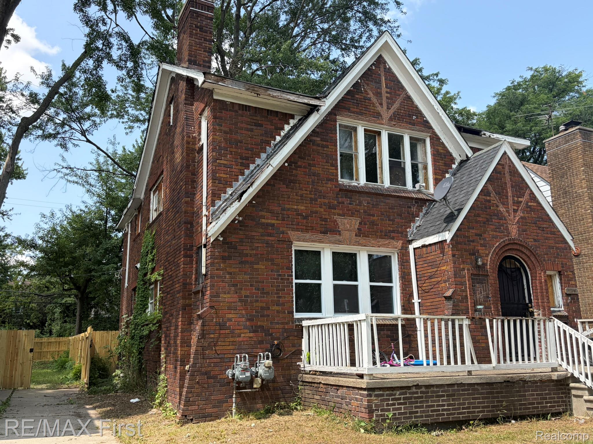 5919 Yorkshire Road Detroit, MI 48224 - Photo 9 of 28 Brick facade residence featuring a front porch with white railing, a gabled entry with an arched doorway, and multiple windows with white trim