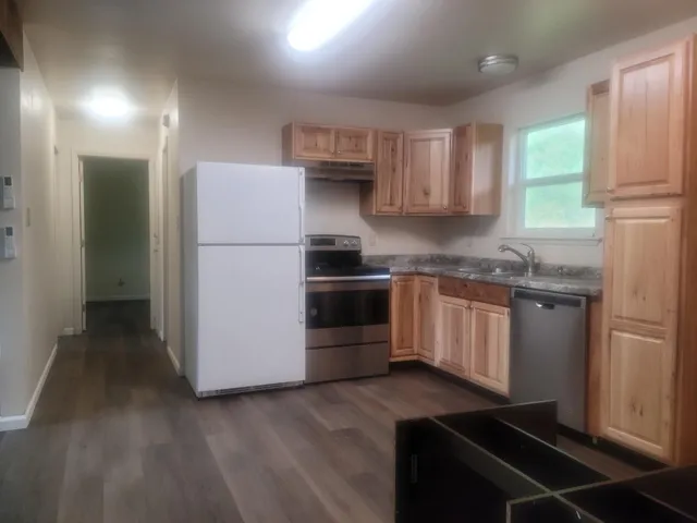 a kitchen with granite countertop a refrigerator stove and sink