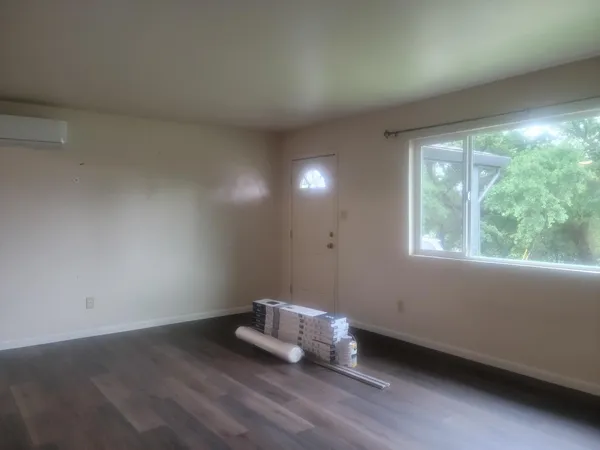 an empty room with wooden floor and windows