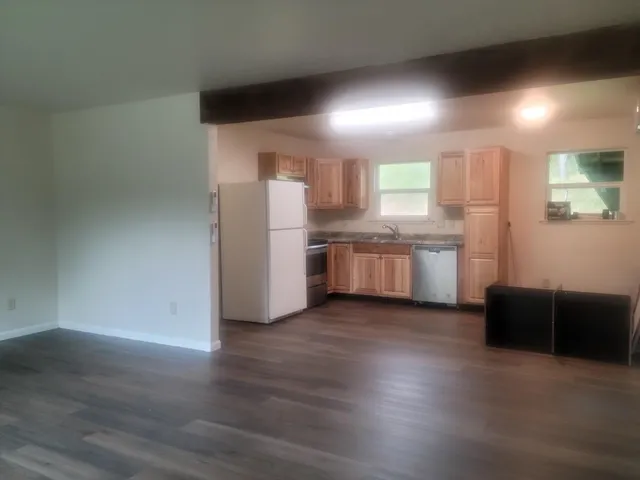 a kitchen with stainless steel appliances wooden floors and white walls