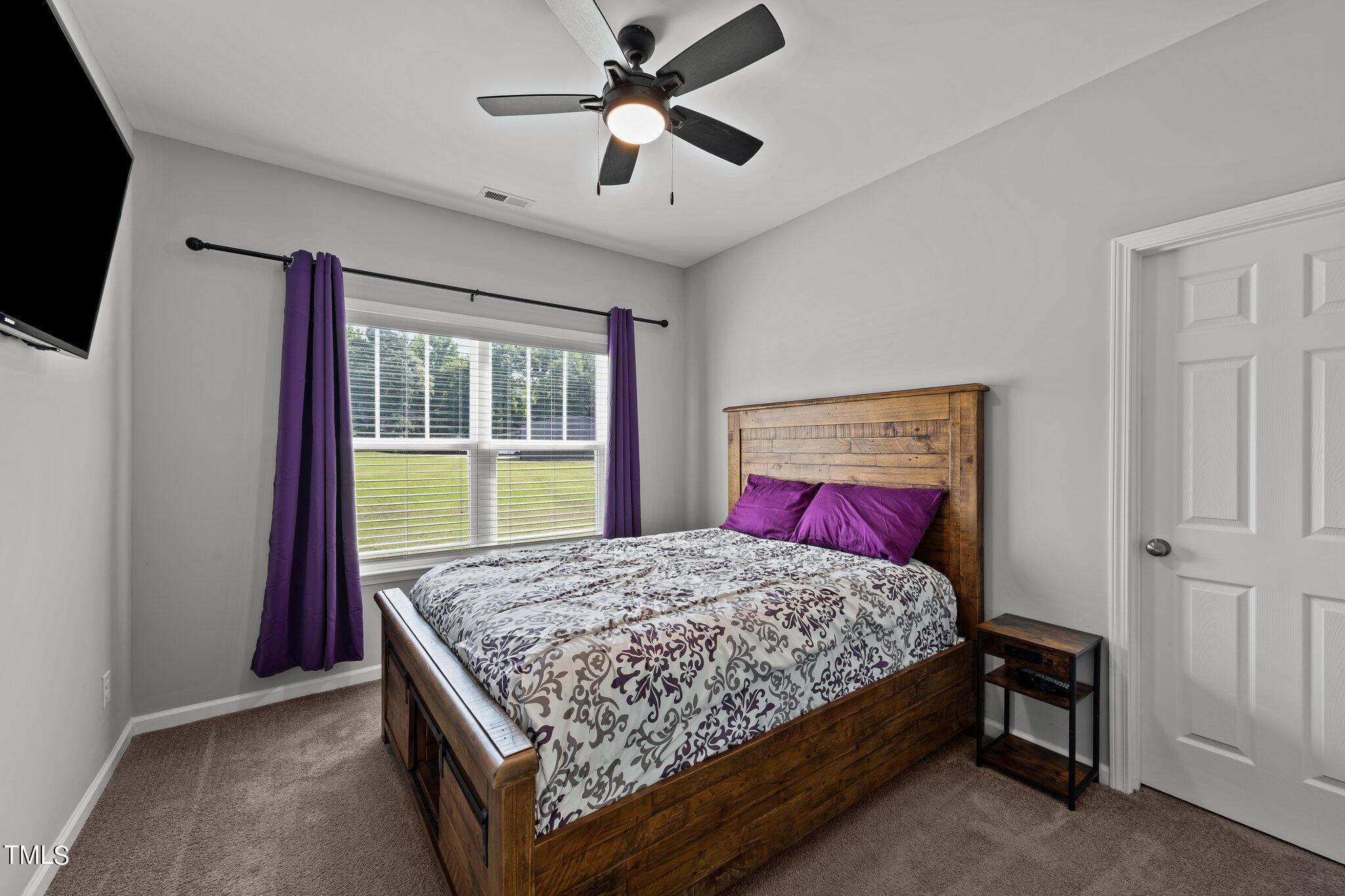 7588 Sadie Road Kenly, NC 27542 - Photo 49 of 58 a bedroom with a bed and a flat tv screen on dresser