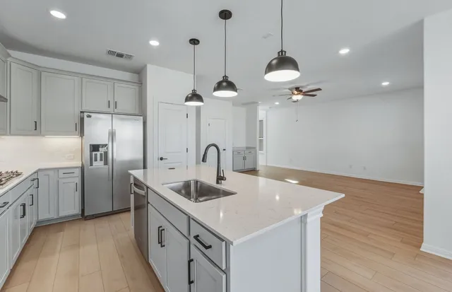 a kitchen with stainless steel appliances granite countertop a sink a center island and a wooden floor