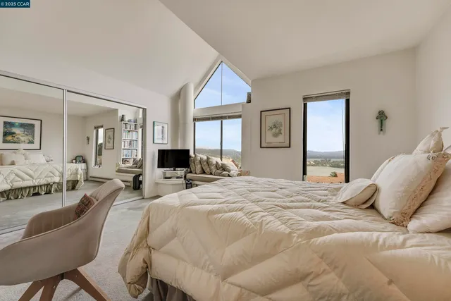 a spacious bedroom with a bed a couch and large window