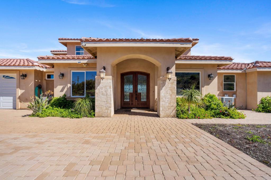 a view of a house with potted plants and a large tree