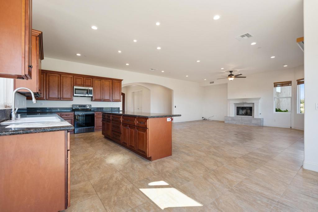 4261 Entrada Al Sol Bonsall, CA 92003 - Photo 15 of 49 a large kitchen with stainless steel appliances kitchen island granite countertop a large counter top and a stove top oven