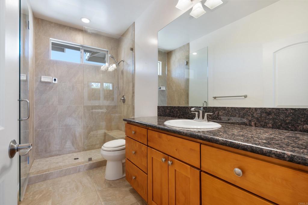 4261 Entrada Al Sol Bonsall, CA 92003 - Photo 29 of 49 a bathroom with a granite countertop sink a toilet a mirror and shower