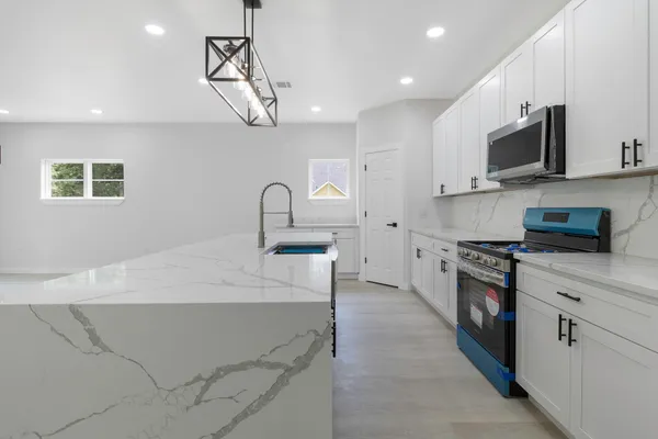 a kitchen with stainless steel appliances granite countertop a sink a stove top oven a counter space and cabinets