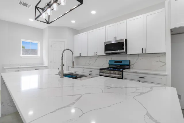 a kitchen with stainless steel appliances granite countertop a stove a sink and a microwave