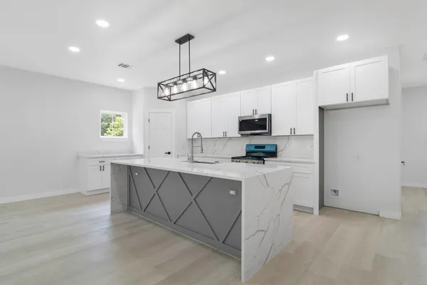 a kitchen with stainless steel appliances a sink a stove a refrigerator cabinets and a window