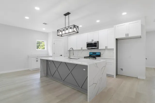 a kitchen with stainless steel appliances a sink a stove a refrigerator cabinets and a window