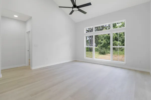 a view of an empty room with a window and wooden floor