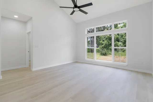 a view of an empty room with a window and wooden floor