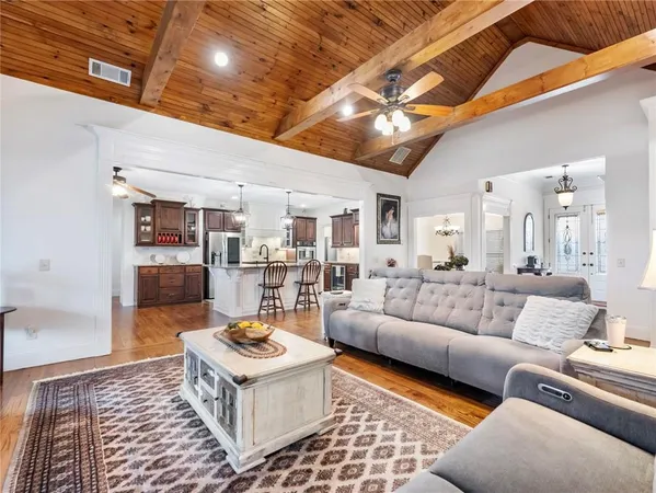 a kitchen with stainless steel appliances granite countertop a stove top oven a sink a dining table and chairs with wooden floor