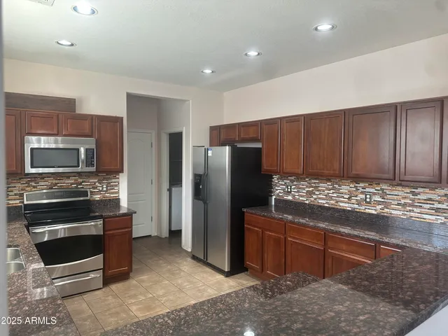a kitchen with stainless steel appliances kitchen island granite countertop a refrigerator and a stove top oven