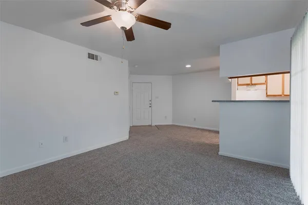an empty room with a chandelier fan and windows