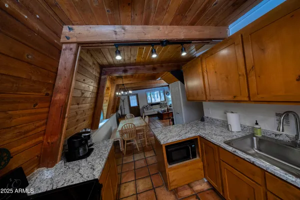 a kitchen with a wooden floor and a view of living room