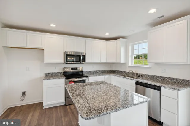 a kitchen with granite countertop a sink cabinets and stainless steel appliances