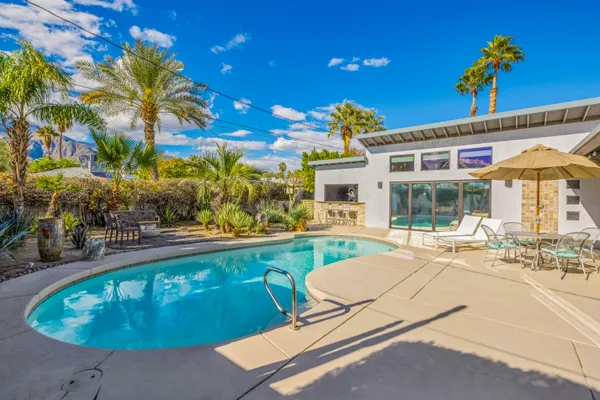 a swimming pool view with a seating space and a garden view