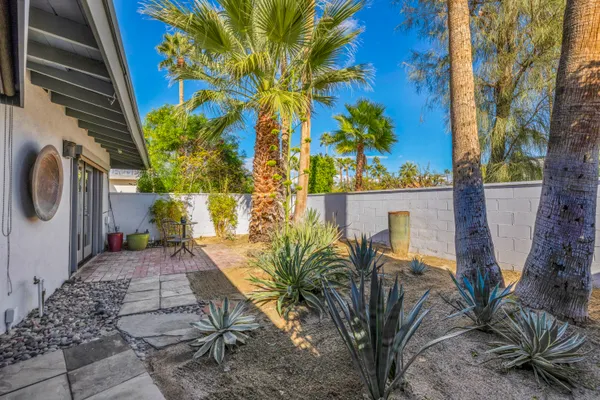 a backyard of a house with table and chairs potted plants