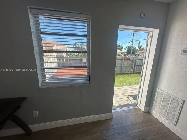 a view of an empty room and outdoor space wooden floor and a kitchen
