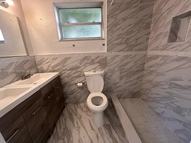 a bathroom with a granite countertop toilet and a sink