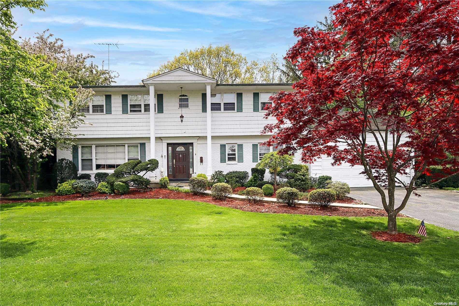 a front view of a house with garden and trees